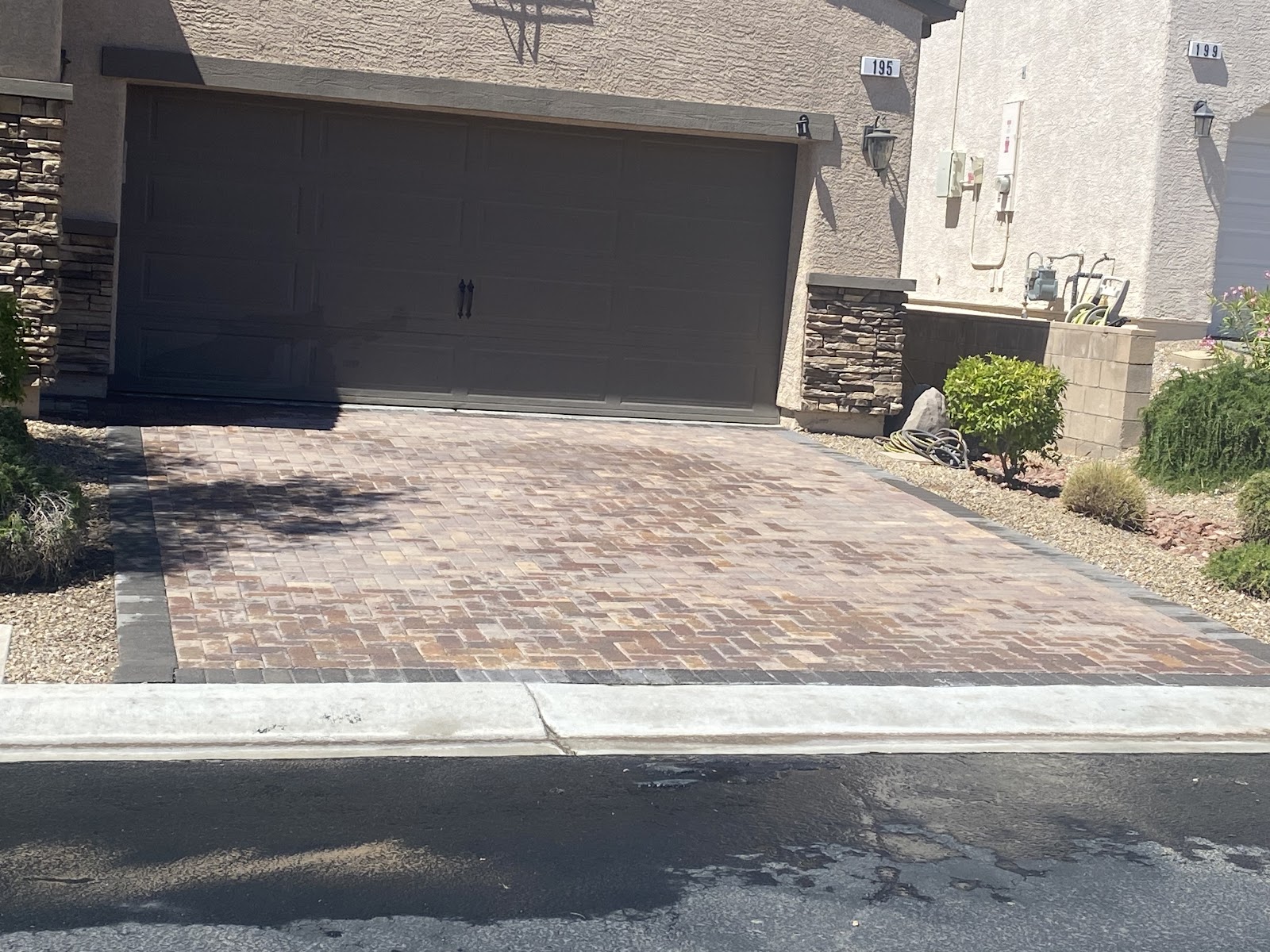 Freshly cleaned paver driveway in front of a two-car garage