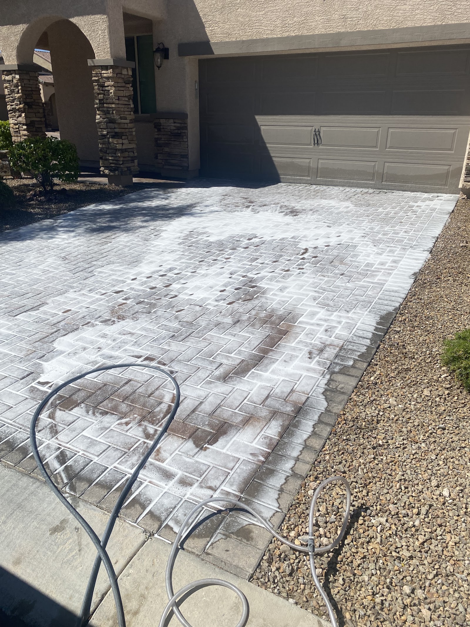 Paver driveway covered in cleaning foam during pressure washing